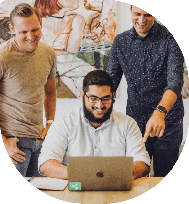 3 man looking at a laptop and smiling